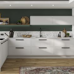 a kitchen with green walls and white cabinets, an area rug and wooden flooring