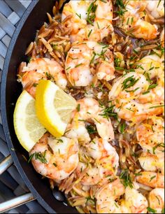 a skillet filled with shrimp, rice and lemon wedges