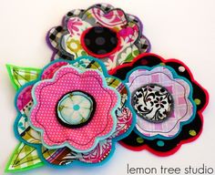 three fabric flower brooches sitting on top of each other