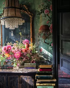 a table topped with lots of books next to a mirror filled with pink and red flowers