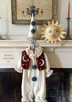 a baby's christmas outfit hanging on a fireplace mantel with a sun and moon decoration above it