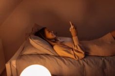 a woman laying on top of a bed next to a white light bulb in a room