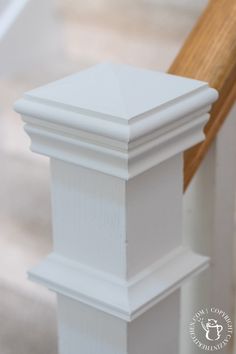 a close up of a white pillar with wood on top