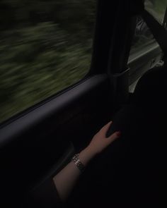 a woman's hand on the dashboard of a car at night with blurry trees in the background