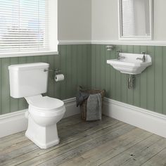 a white toilet sitting in a bathroom next to a sink under a window with shutters