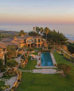 an aerial view of a house with a swimming pool in the foreground and ocean in the background