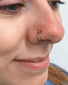 a close up of a person with a nose ring on their nose and one eye open