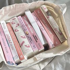 a bunch of books that are sitting in a bag on a bed with white sheets