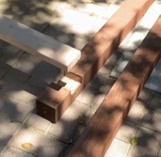 two benches sitting next to each other on top of a stone floor in the shade