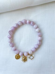 Soft purple kunzite beads make of this beautiful lavender beaded bracelet set with celestial charms. These bracelets are stretch bracelets and include star, moon and sun charms. Each piece is designed and handmade in Brooklyn. After visiting the Notre Maison orphanage in 2015, I fell in love with the children and knew I wanted to help sponsor them. That's what started this shop. Every purchase helps us sponsor 5 children at the orphanage that we follow up with and visit over the summers. Join ou Celestial Style Beaded Bracelets As Gift, Handmade Celestial Beaded Bracelets With Round Beads, Handmade Celestial Beaded Bracelets For Gifts, Adjustable Beaded Bracelets With Moon Charm, Handmade Lavender Stretch Bracelet With Round Beads, Adjustable Spiritual Beaded Bracelet With Moon Charm, Lavender Beaded Bracelet, Gold Beaded Bracelet, Moon And Sun