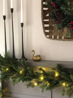 a mantle with candles and christmas garland on it