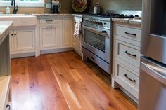 a kitchen with white cabinets and wood floors