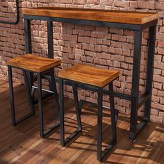 two wooden stools sitting on top of a hard wood floor next to a brick wall