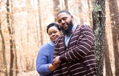 a man and woman standing next to each other in the woods