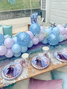 a frozen princess themed party with balloons and plates on a table in front of a house