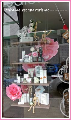 there is a display in the window with pink flowers and dolls on shelves next to it