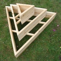 three wooden boxes stacked on top of each other in the middle of a grass field