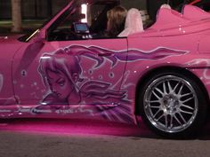 a pink car that has been painted with graffiti