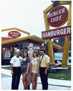 some people are standing in front of a hamburger restaurant and posing for a photo with the sign behind them