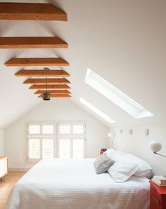 an attic bedroom with white walls and wooden beams on the ceiling, along with a bed