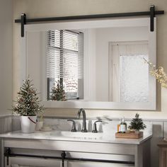 a bathroom with a sink, mirror and christmas trees in the window sill on the wall