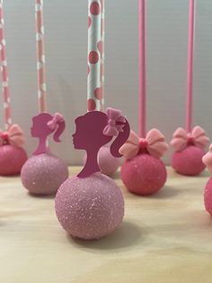 pink and white cake pops with silhouettes of women on them in front of candles