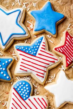 decorated cookies with stars and stripes are on a piece of parchment paper in the shape of an american flag