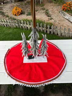 two fake trees are sitting on top of a red tablecloth with white trimmings