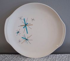 a white plate with blue and gold designs on it sitting on a table next to a gray wall