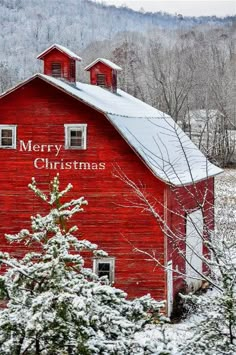 a red barn with snow on the ground and trees in front of it that says merry christmas