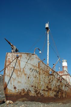 an old rusted boat sitting on the beach