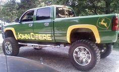 a green and yellow truck parked in front of trees