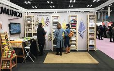 two people standing in front of a booth at a trade show looking at items on display