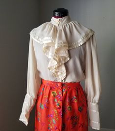 "ERA 1970s DESIGNER Andree Gay for the Shirt Off My Back  COLOR Cream MATERIALS 100% Polyester  SIZE Labeled Size: 7/8 💋Vintage Sizes are NOT Comparable to Modern Sizes Please compare our measurements listed with your own to ensure proper fit! MEASUREMENTS 💋Please ONLY Go off of the Measurements Provided to Ensure Proper Fit.  Bust 40\" Waist 39\" Length 20.5\" Arm Inseam 18.5\" DESCRIPTION  Beautiful Ruffled Blouse Designer Vintage Piece Victorial Style Flowy fabric Blossomy Sleeves Tapered W Vintage Blouse With Ruffled Collar For Work, Vintage Ruffled Collar Blouse For Workwear, Vintage Blouse With Ruffled Collar And Button Closure, Retro Blouse With Peter Pan Collar, Retro Blouse With Ruffled Collar, Retro Blouse With Peter Pan Collar For Vintage Fashion, 1970s Vintage Fashion Tops For Spring, Vintage Button-up Blouse, Retro Spring Blouse With Buttons