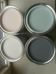 four different colors of paint sitting on top of a window sill next to a door