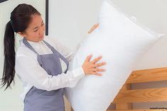 a woman holding a large white pillow in her hands