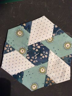 a hexagonal patchwork piece is laying on top of a black table cloth