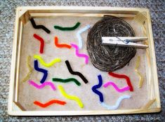 the scissors are laying next to some yarn and twine in a tray on the floor