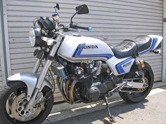 a white and blue motorcycle parked in front of a garage