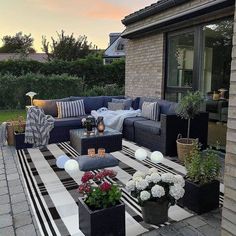 an outdoor living area with black and white striped rugs, potted plants, and couches