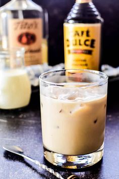 an alcoholic drink is sitting on the table next to some liquor bottles and spoons