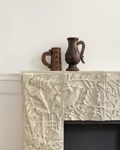 a white fireplace with vases on top of it