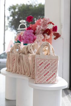 several bags are lined up on a table with flowers in the background