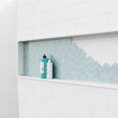 a bathroom with white tiles and blue bottles on the window sill next to it