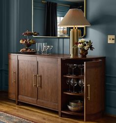 a buffet table with wine glasses on it and a lamp in the corner next to it