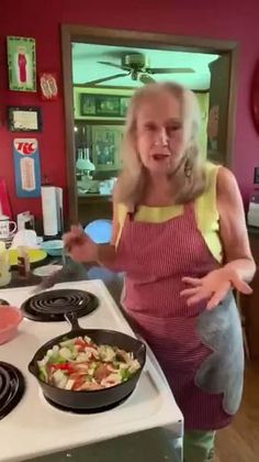 a woman standing in front of a stove with food on top of it and pointing to the side