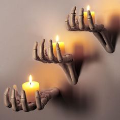 three candles are arranged in the shape of hands with fingers on each hand and one candle is lit