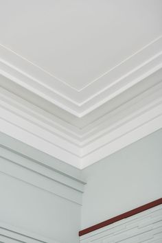 the corner of a room with white painted walls and wood trimming on the ceiling