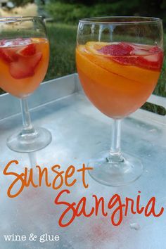 two glasses filled with wine and fruit sitting on top of a metal tray next to each other