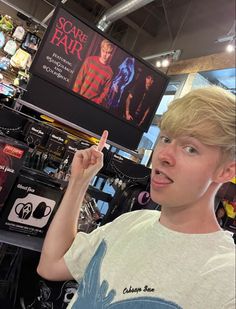 a young boy is pointing to the screen in front of him at an electronics store